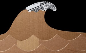 Photo of 2 rows of waves cut out of cardboard boxes, with large cardboard tsunami wave that has a white crest made of white/black shipping label