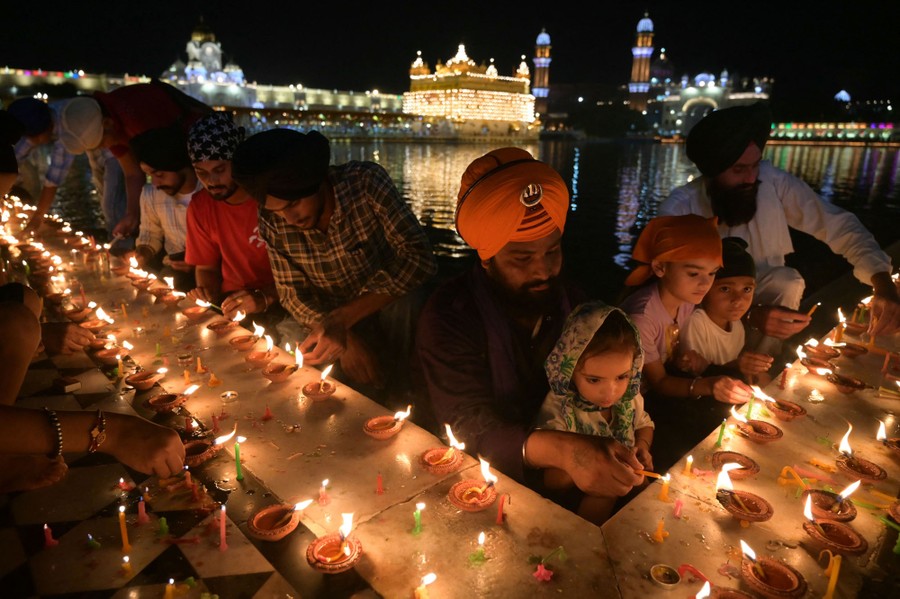 People gather to light small oil lamps outside a temple.