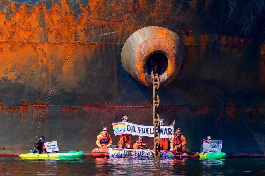 About seven protesters in three small boats stage a demonstration beside a massive oil tanker.