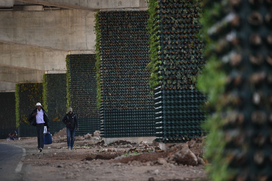 Two people walk beneath a newly constructed highway overpass.