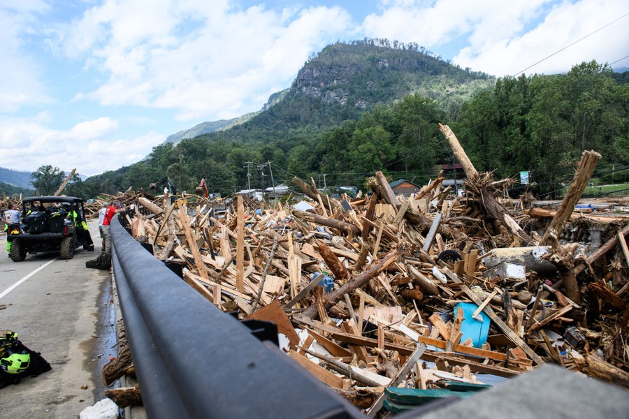 Huge piles of debris sit bunched-up against a road bridge.