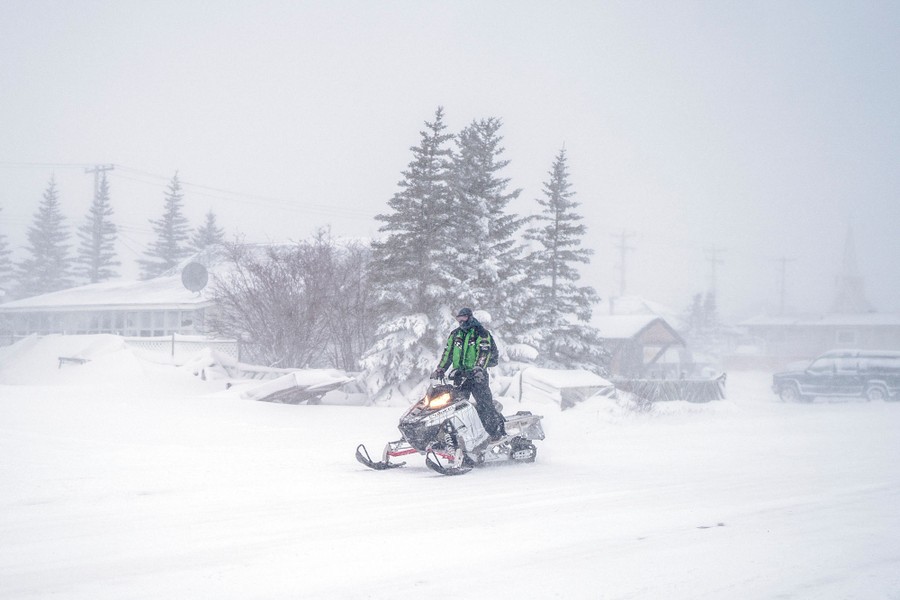 A person rides a snowmobile on a road during a snowstorm.