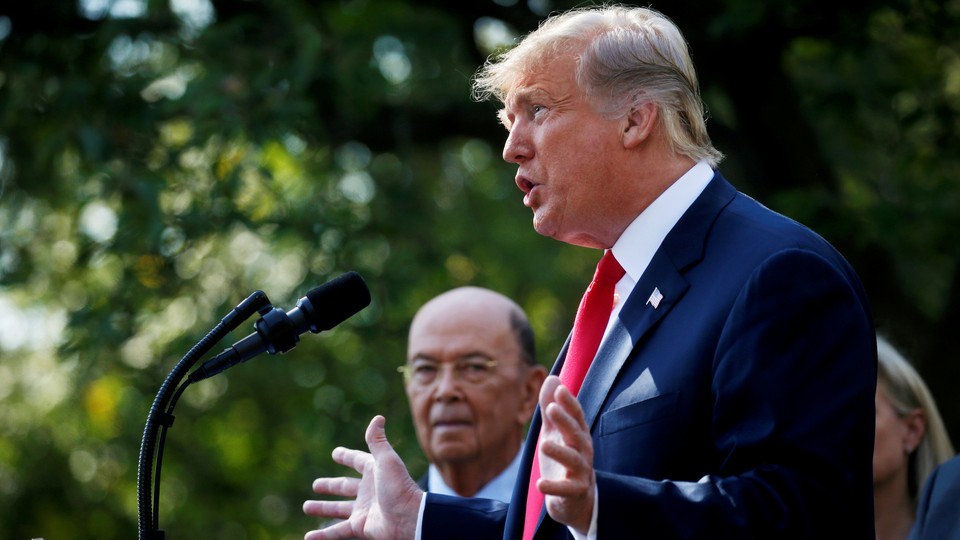 President Donald Trump announces a policy as Commerce Secretary Wilbur Ross looks on