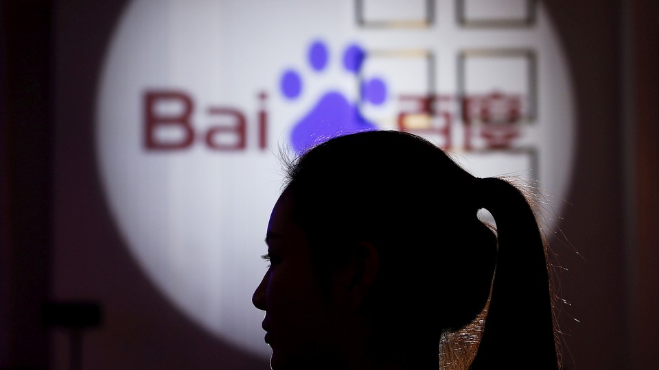 A woman is silhouetted against the Baidu logo