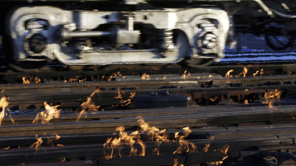 A train moves past rails surrounded by flames.