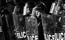A black-and-white photo of a line of police officers with shields