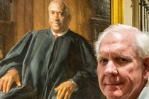 Picture of Harlan Crow in front of a painting of Justice Clarence Thomas