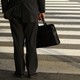 A businessman waits on a street corner. 