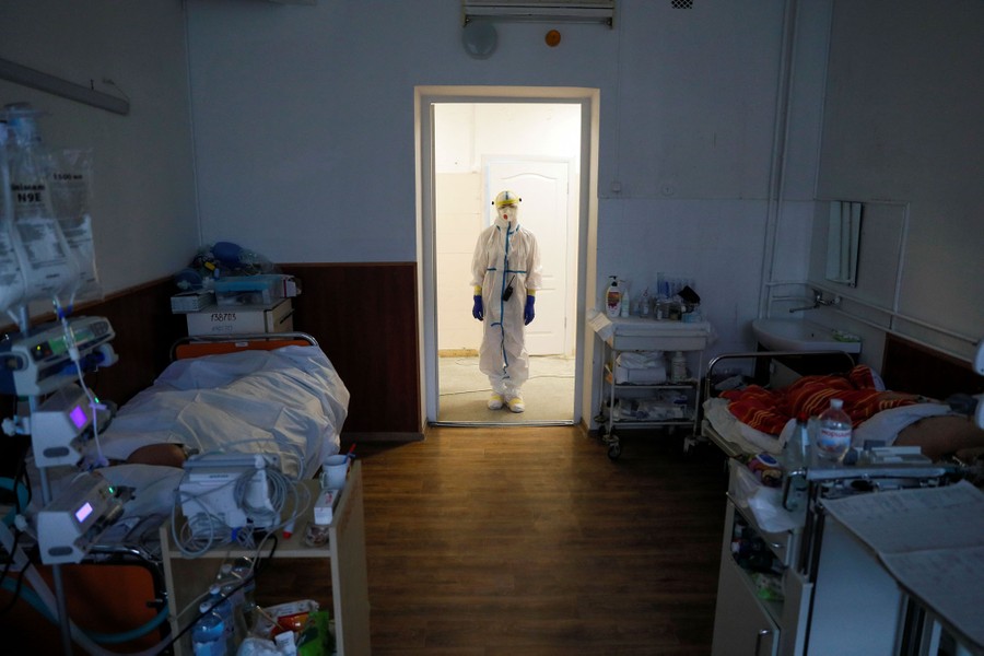 A person stands in a doorway in a hospital wearing protective equipment.