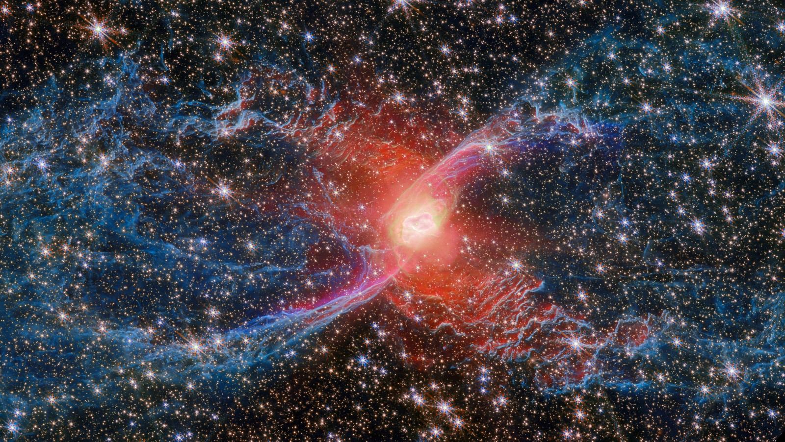 A bright red cloud appears at the center of a roughly spider-shaped trail of gas and dust, backdropped by many other stars.
