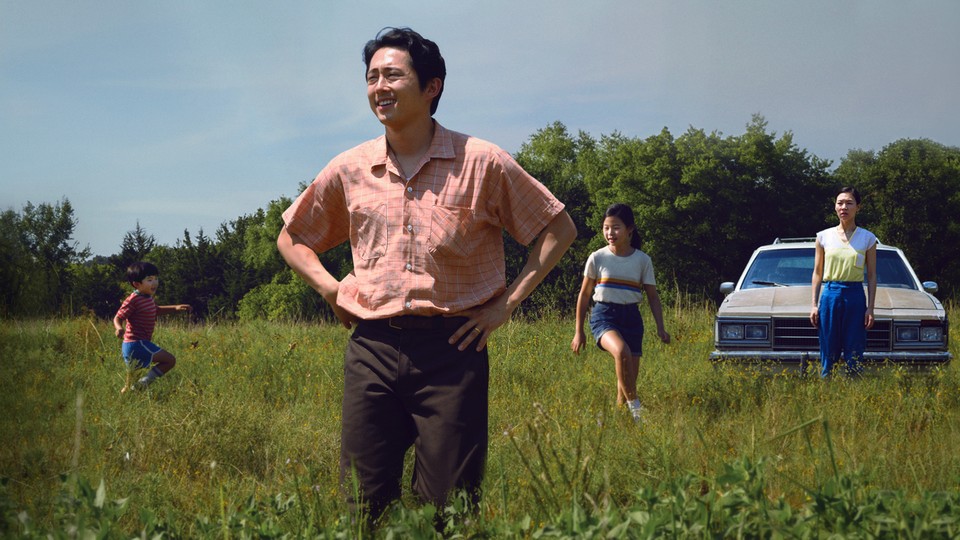 The Yi family stands in a field in front of their car