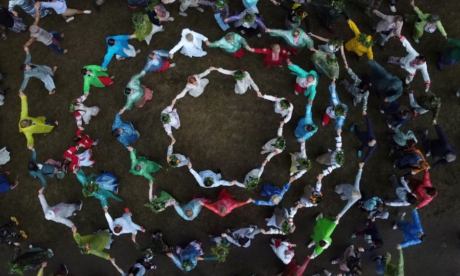 An aerial view of dozens of people joining hands in circles