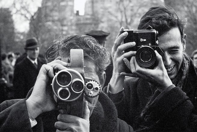 photo of two men very close up, with cameras pointing directly at camera