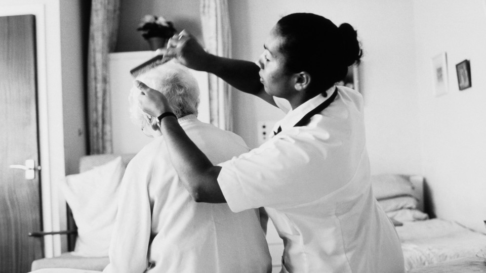 A health aide helps comb the hair of an elderly person