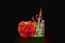 Image of an apple and a cup of desk supplies, in pixelated form with 1s and 0s