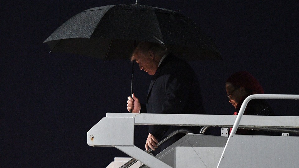 President Trump carrying a black umbrella as he disembarks Air Force One