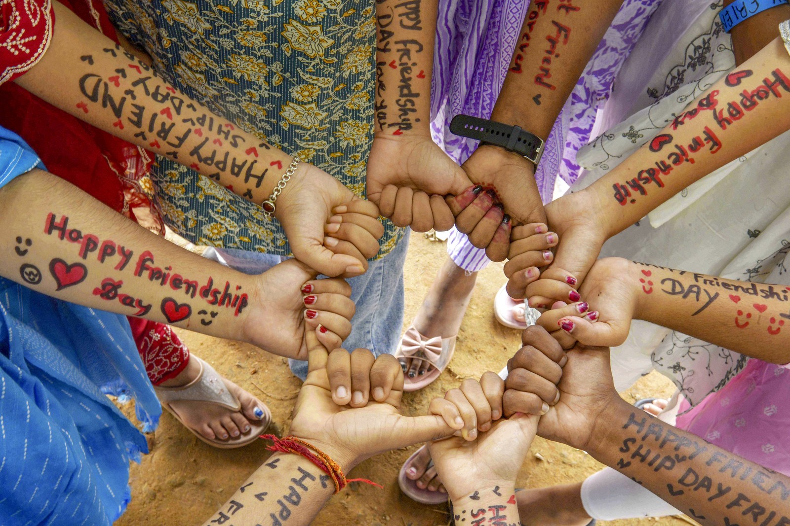 A group of school students celebrate Friendship Day by writing friendship messages on each other’s arms.