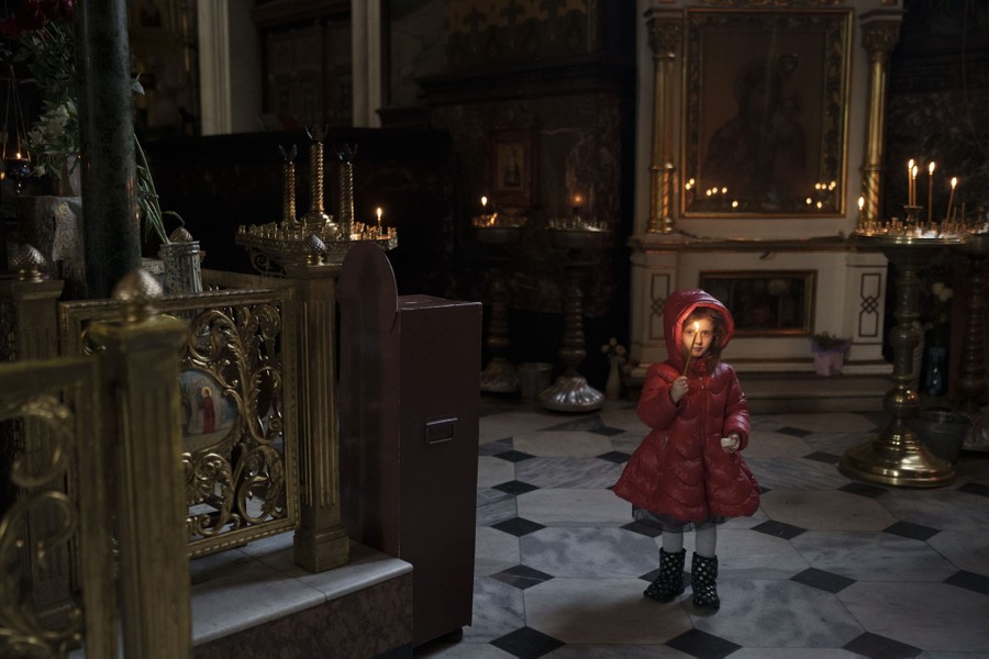 A young girl carries a candle inside a cathedral.