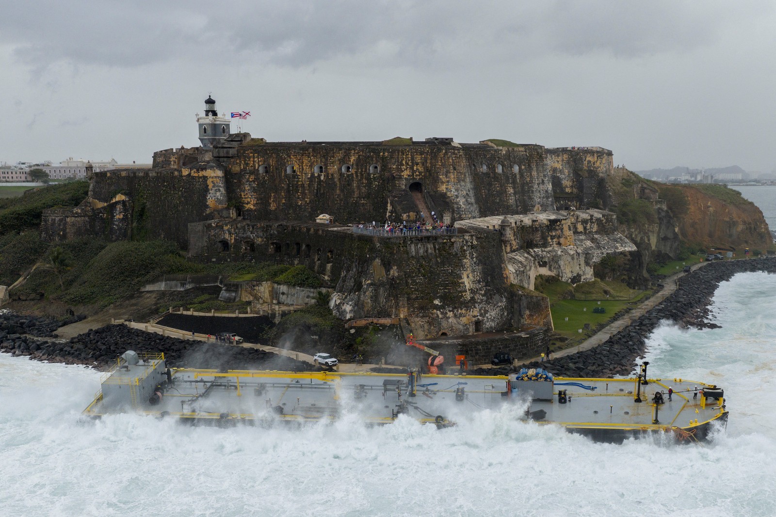 A drone view shows waves crashing over a fuel barge after it ran aground near a historic fortress in Puerto Rico.