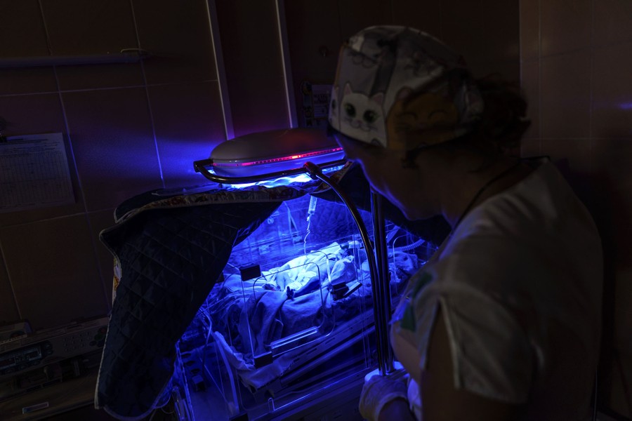 A doctor attends to a prematurely born child being given phototherapy.
