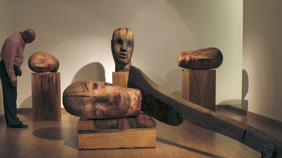 A large wooden sculpture by Mustafa Al depicts heads severed by an axe.