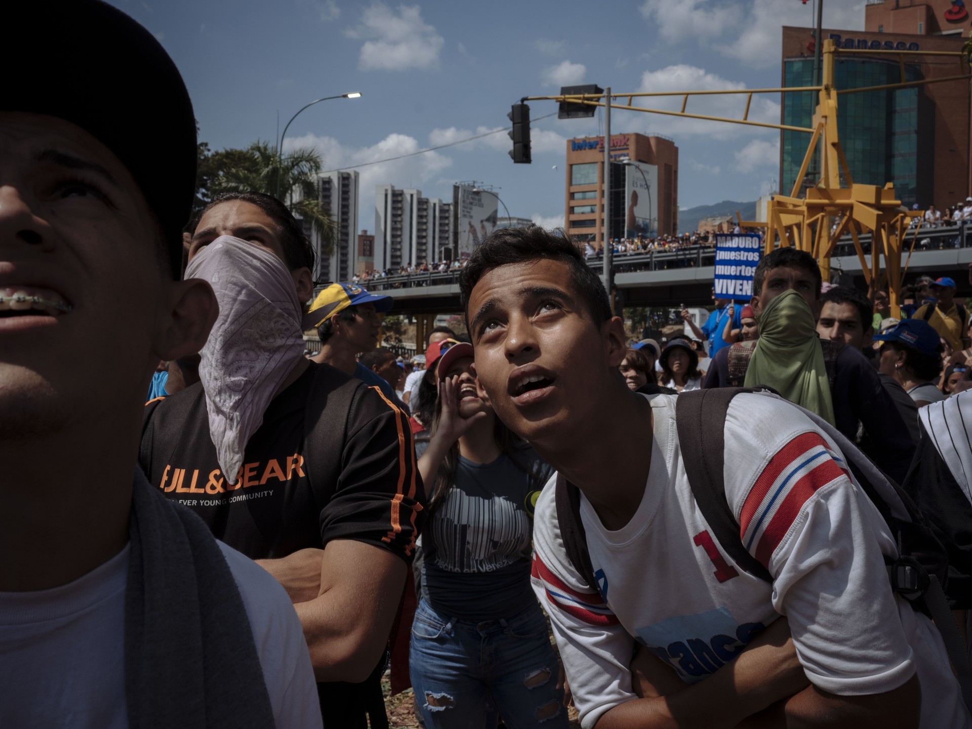 Protestors look at a flag of Maduro burning near Las Mercedes in Caracas.