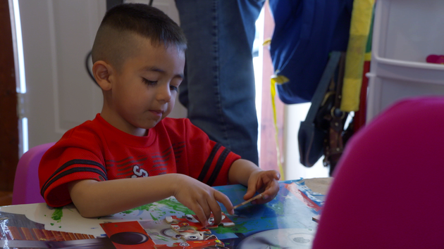 A young boy sits at a table and works on a puzzle. 