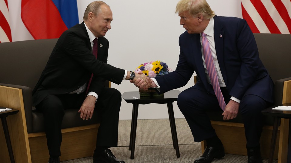 Trump and Putin, seated, shake hands.