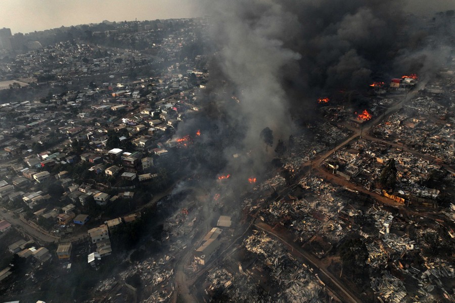 An aerial view of fires burning many houses in a hillside neighborhood