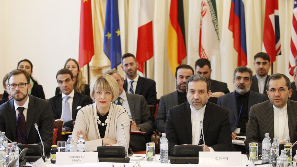 EU and Iranian delegates sitting at a table with flags behind them.