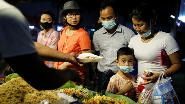 A family wearing face masks buys food from a stall in Yangon, Myanmar.