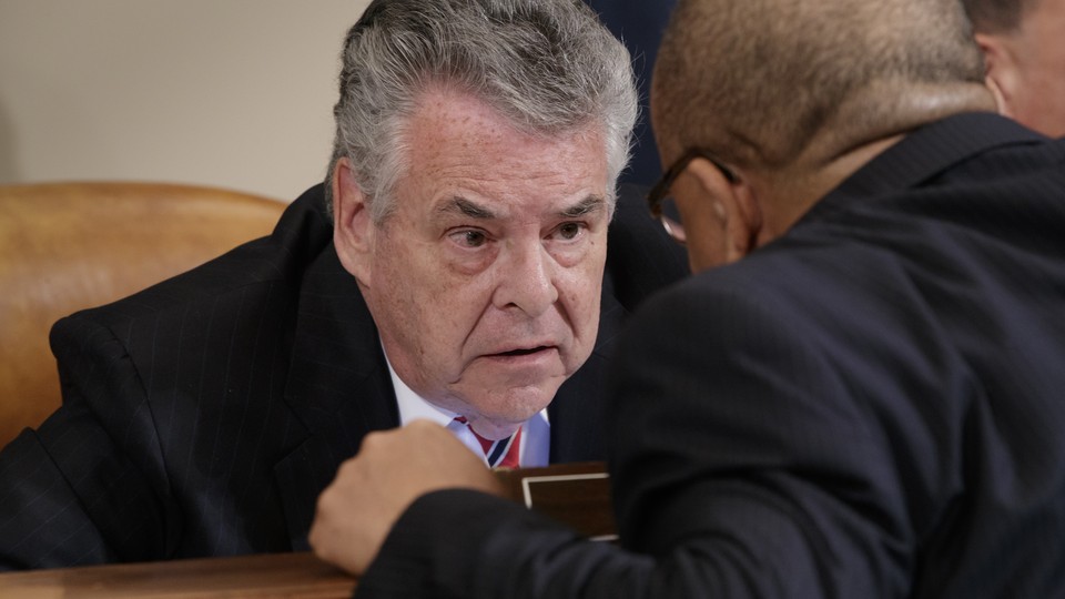 Representative Peter King of New York speaking with a colleague in a congressional hearing room
