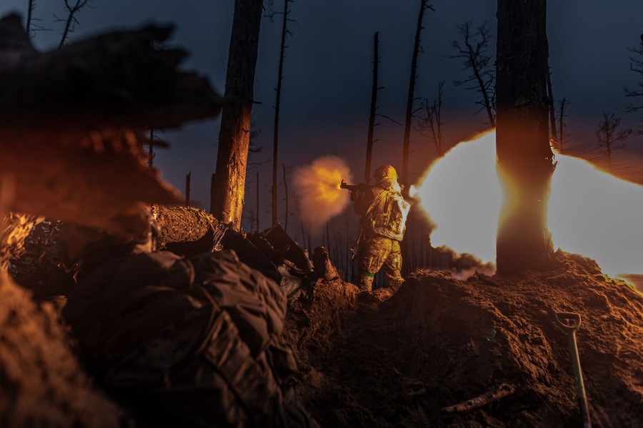 A soldier stands in a trench in a forest, firing a rocket-propelled grenade at night.