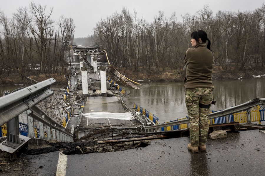A soldier looks at a destroyed bridge.