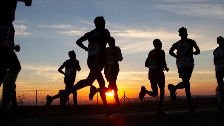 Silhouettes of people jogging along a road