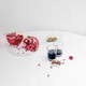 A white table with a pomegranate sliced down the middle on a white plate, and two glasses of pomegranate juice