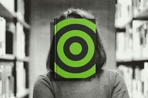 a librarian with a book obscuring her face—the book's cover is a target