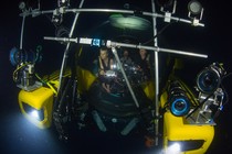 People in a submersible with lots of lights and cameras