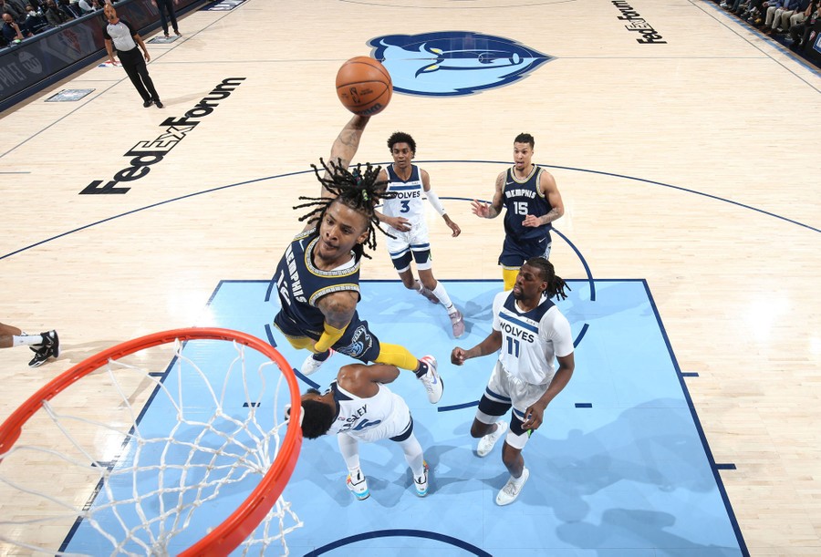 A basketball player jumps over an opponent on his way to dunk the ball.