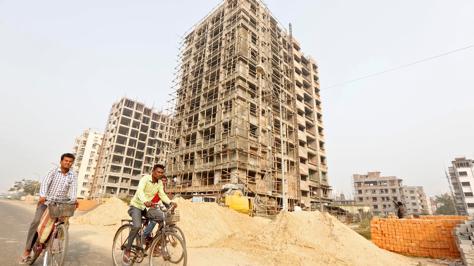 Men ride their bicycles past residential buildings under construction on the outskirts of Kolkata, India, on February 1, 2017.