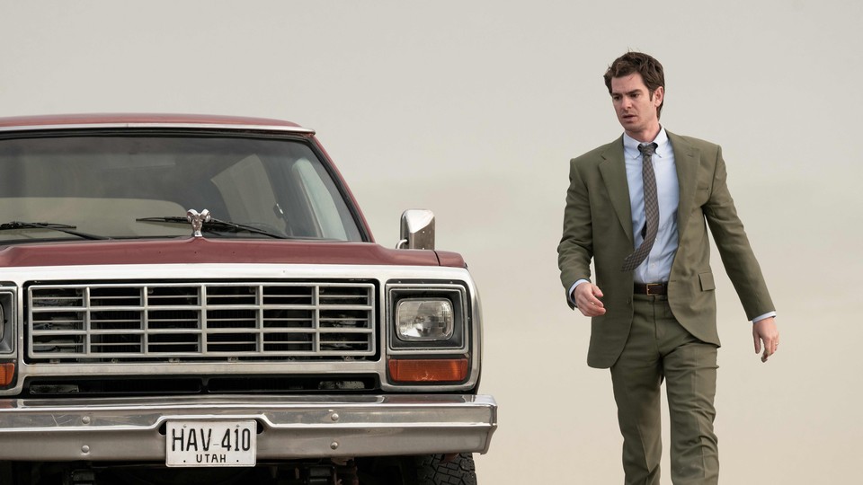 Andrew Garfield's character standing beside a car