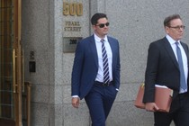 A man in sunglasses and a suit and tie leaves a building marked "500 Pearl Street."