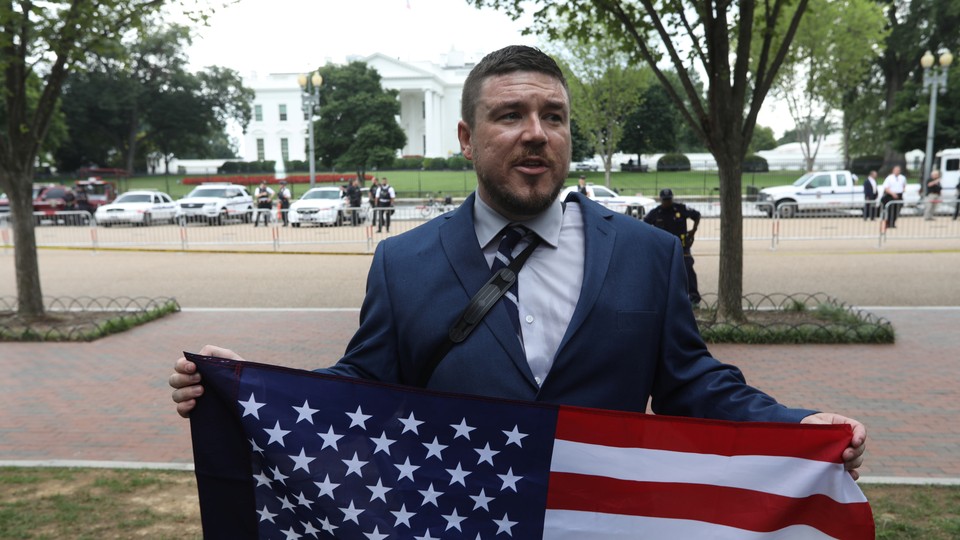 White-nationalist leader Jason Kessler poses with a flag across from the White House.