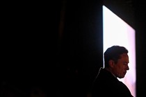 Elon Musk's head is framed in a bright quadrilateral figure cut into a dark background.