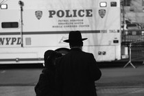 Picture of an orthodox family facing a police car.