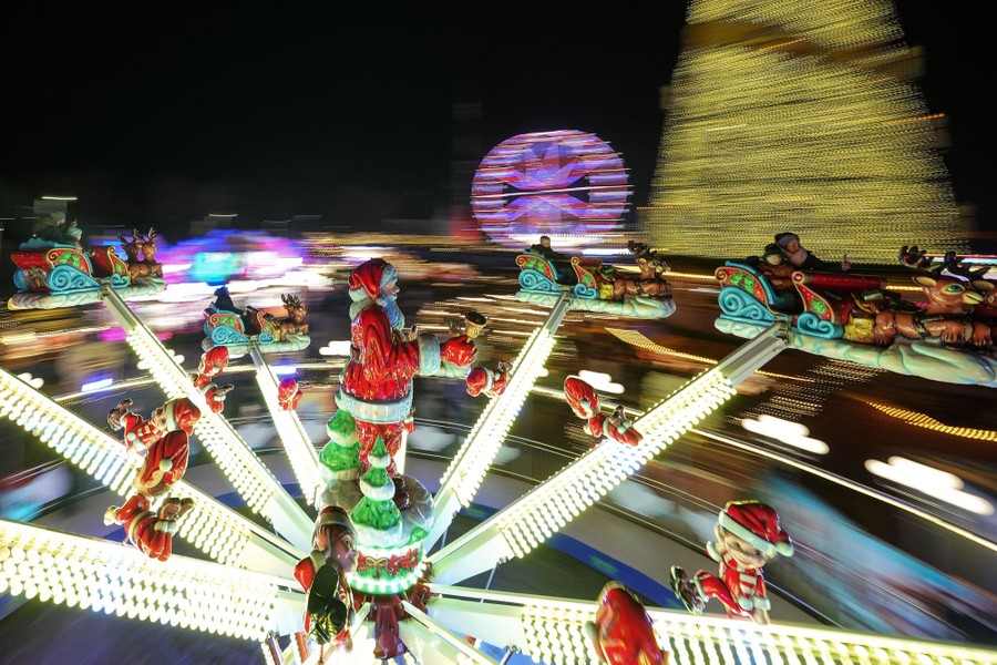 People ride on a Santa Claus–themed carnival ride at night.