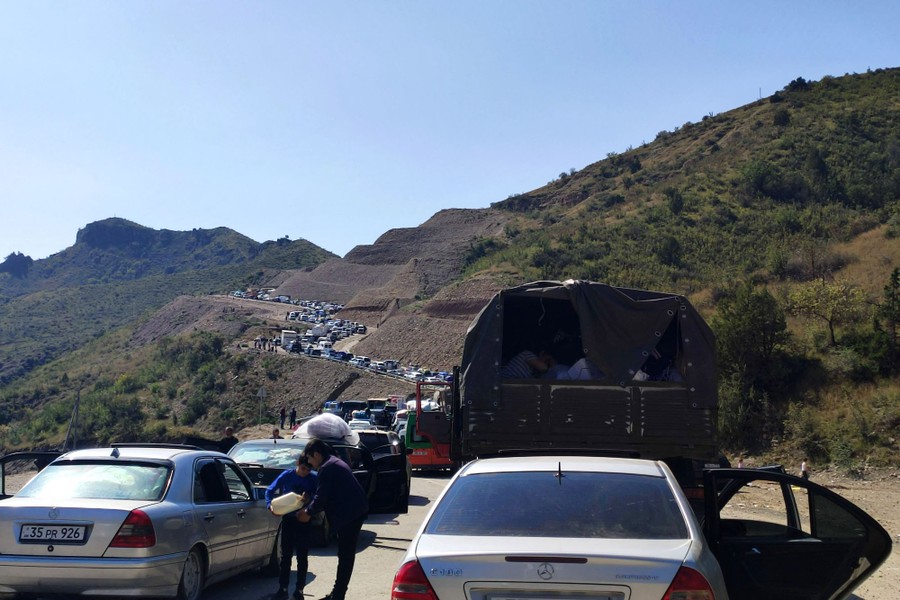 Dozens of cars and trucks sit in a long traffic jam on a curving mountain road.