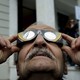 A man looks through eclipse glasses.