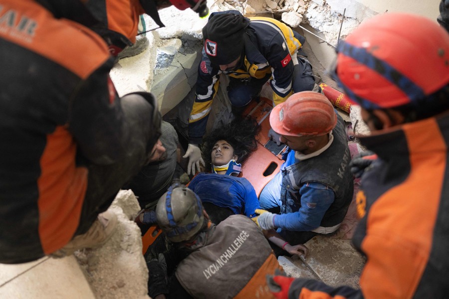 A crew of rescue workers carefully extracts a teenage girl from the rubble of a building.