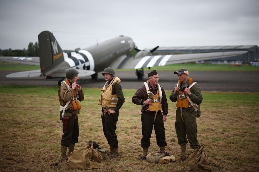 World War II reenactors pose for a photograph beside a vintage aircraft.